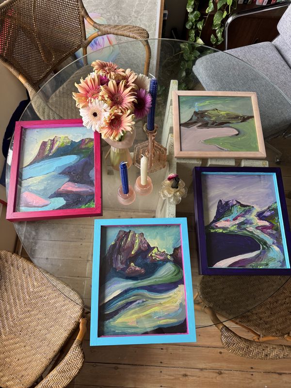 Several small framed landscape paintings laid out on a table